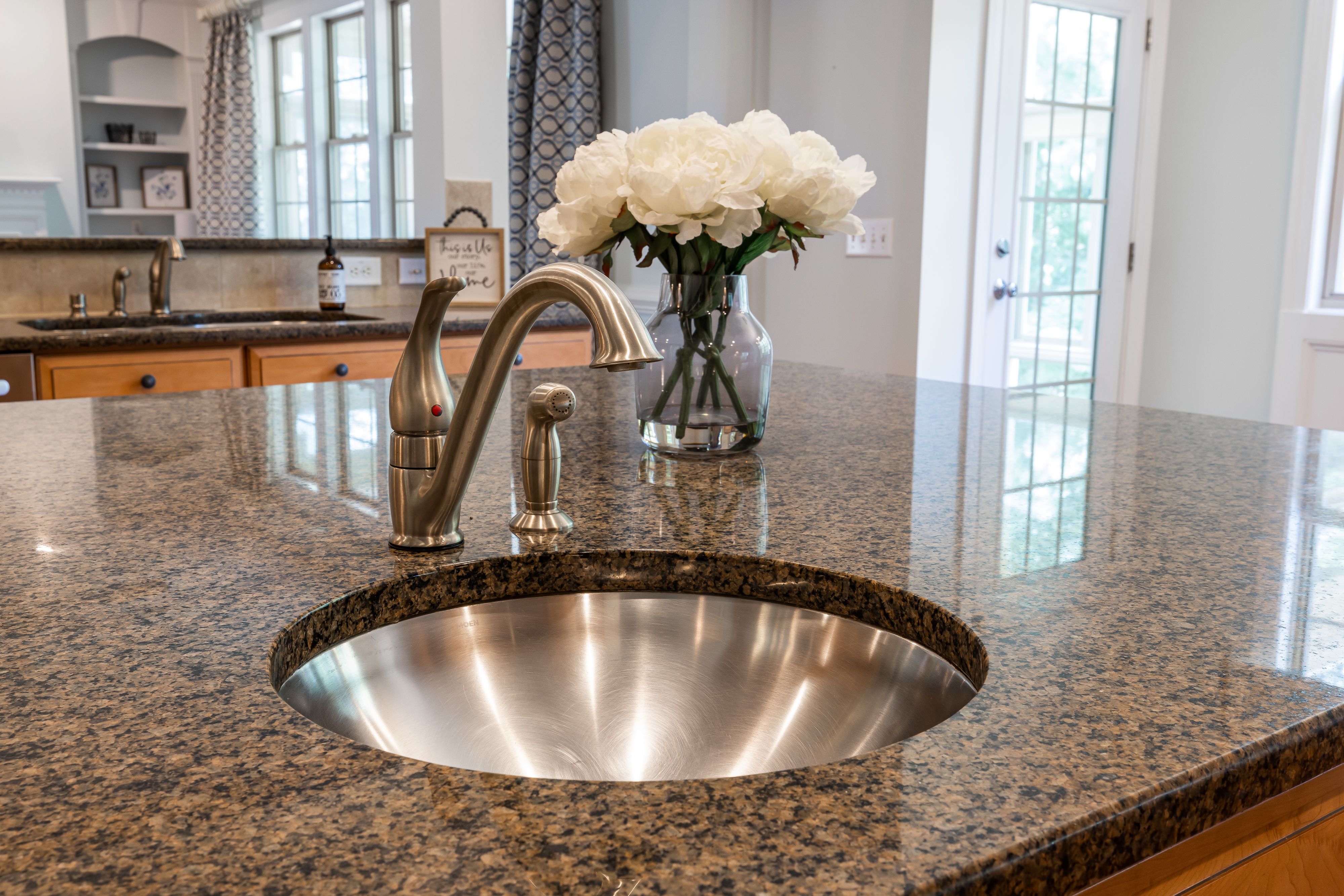 Brown speckled granite kitchen island countertop with a round stainless steel sink