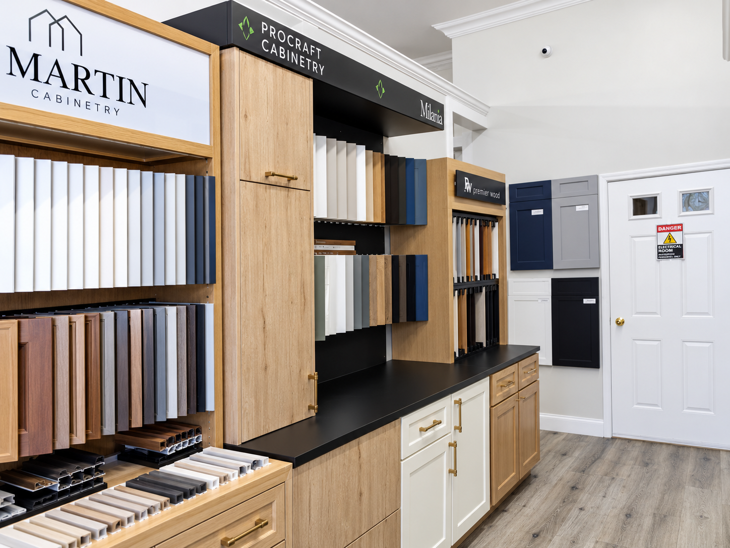 Gray and white kitchen cabinet displays with a wood island at the Kitchen Factory Newark showroom