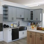 Gray and white kitchen cabinets with a wood island and white countertops at the Kitchen Factory Newark showroom