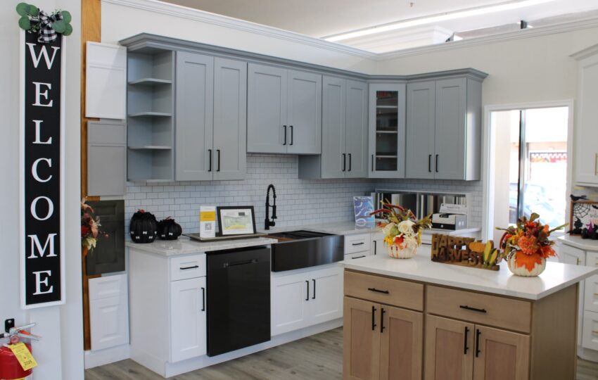 Gray and white kitchen cabinets with a wood island and white countertops at the Kitchen Factory Newark showroom