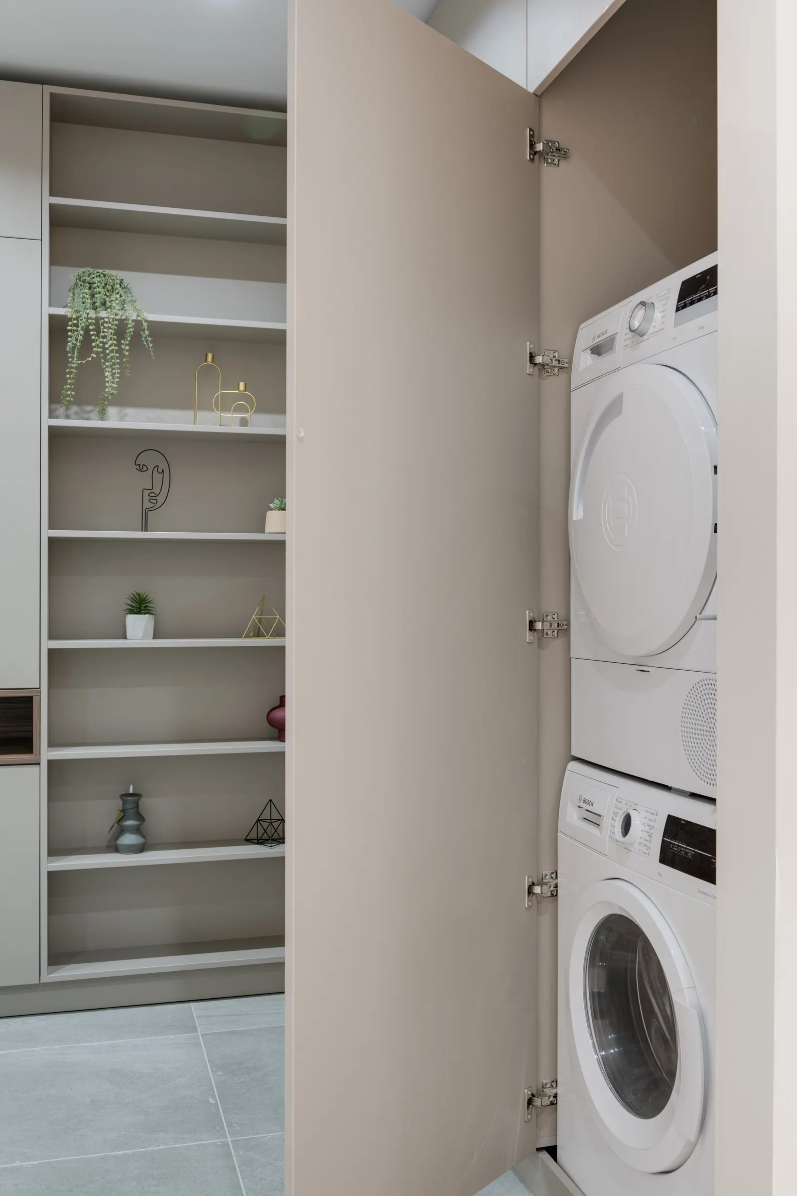 Laundry closet with open shelves and a stacked washer and dryer
