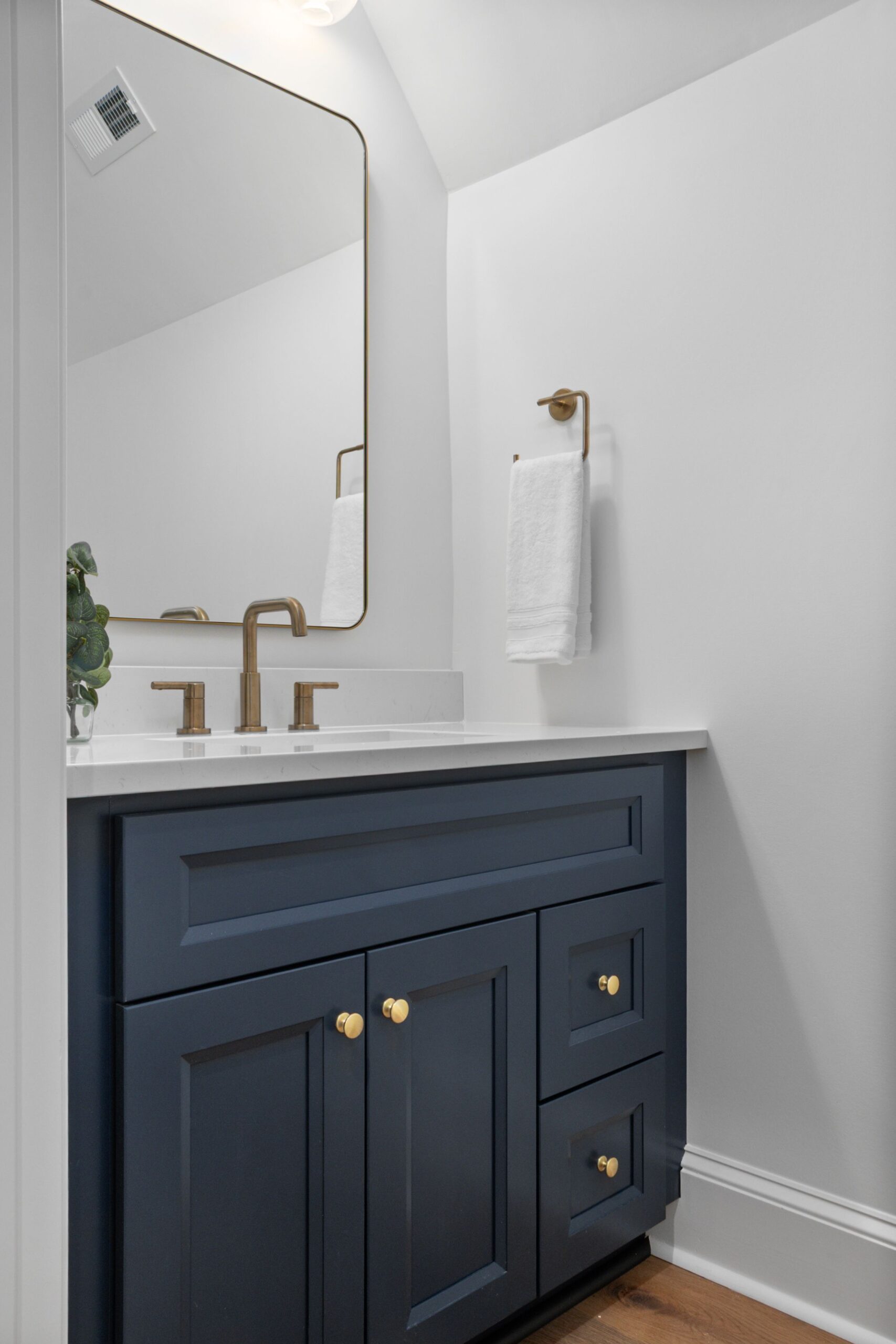 Navy powder room vanity with raised-panel doors and brass knobs
