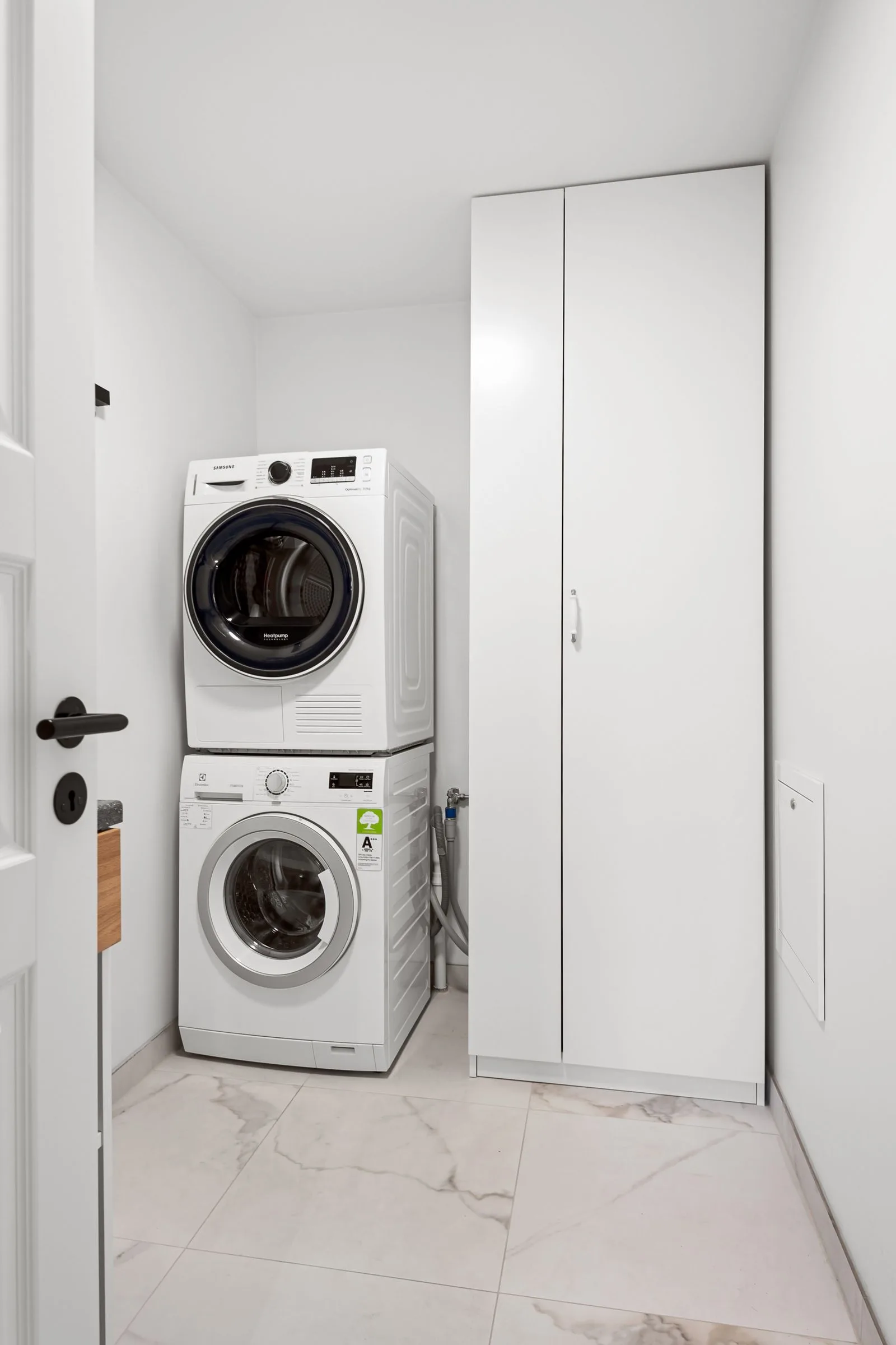 Stacked washer and dryer between tall white laundry cabinets