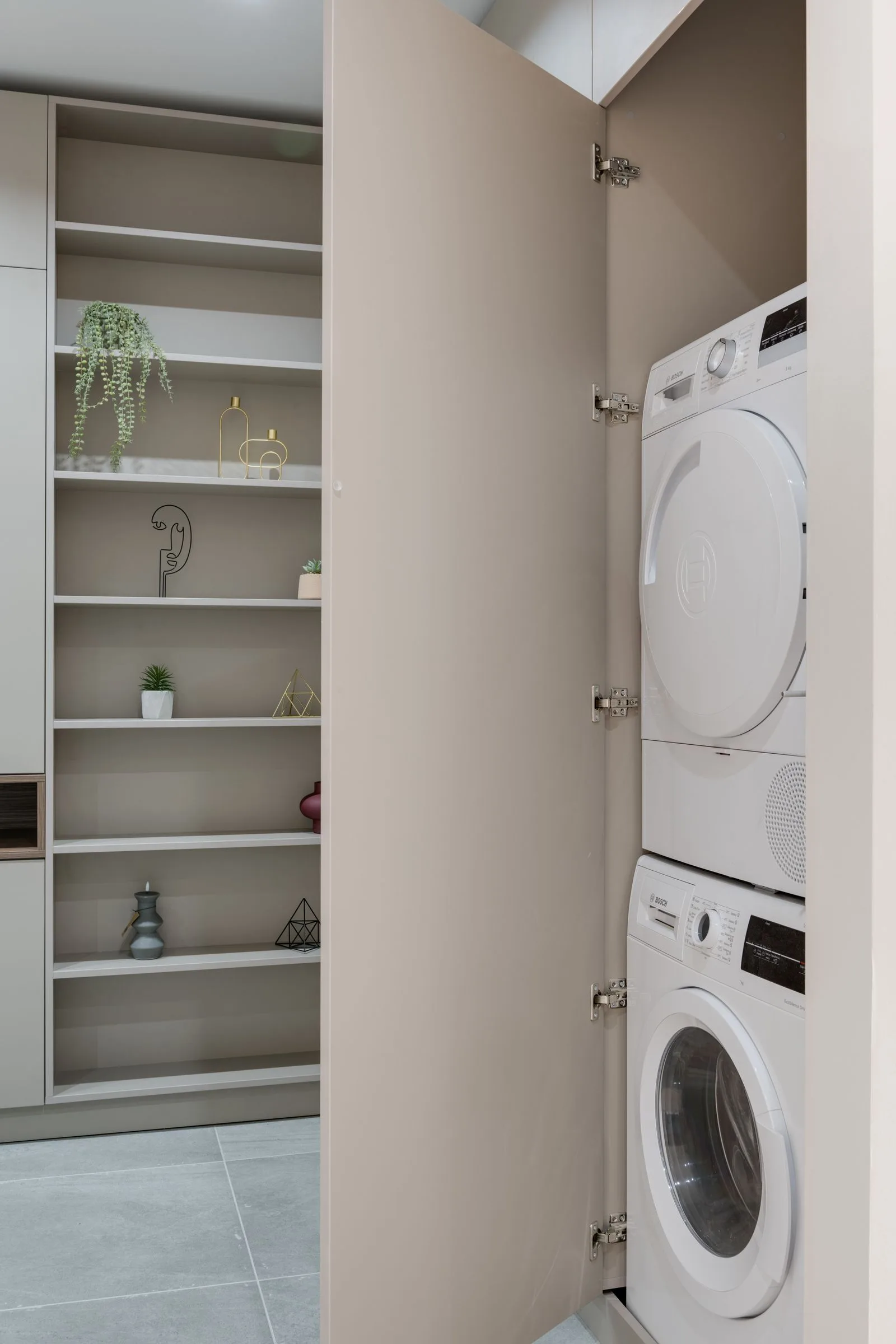 Washer and dryer built into a white laundry cabinet with open shelves