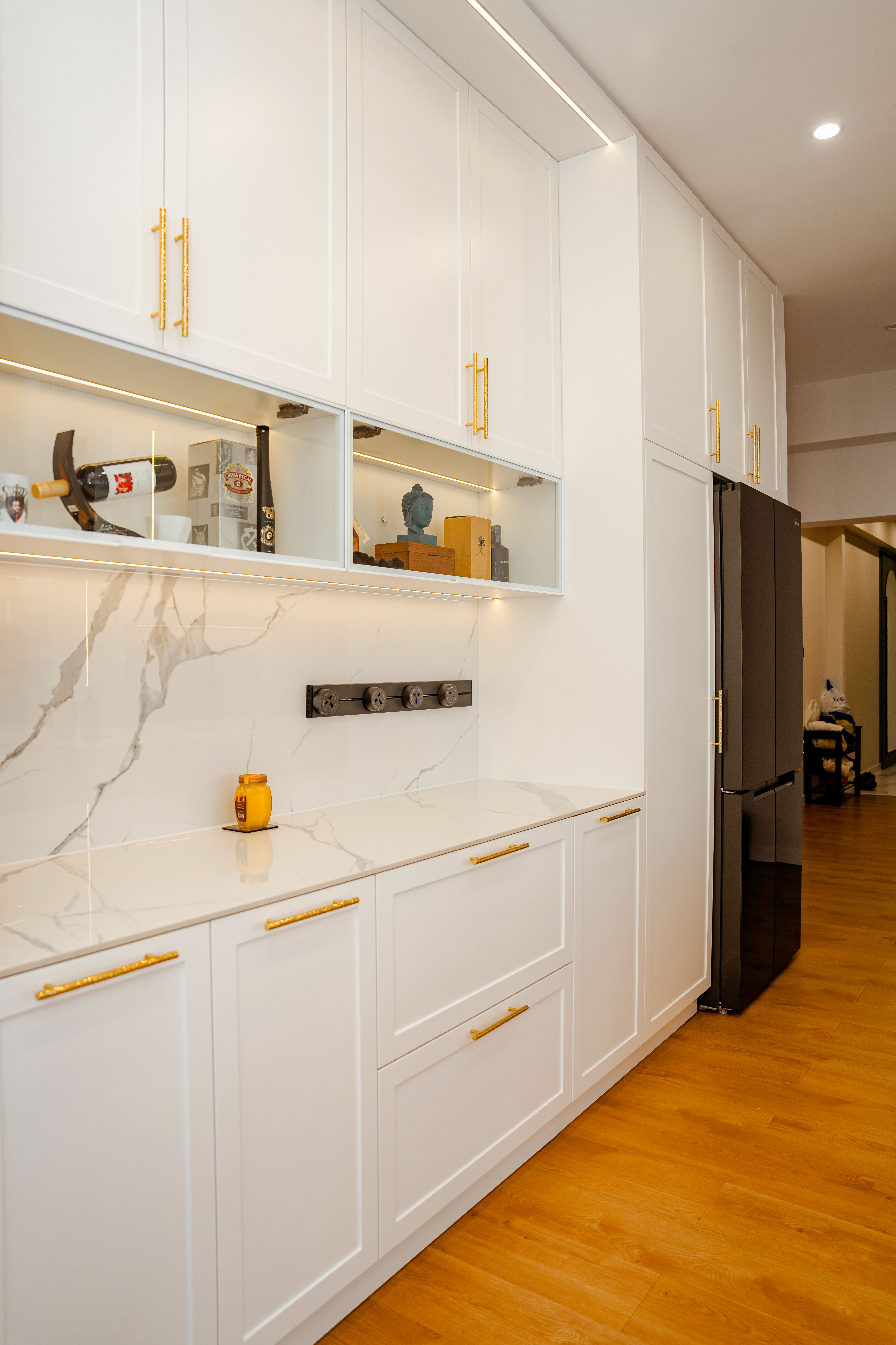 White gloss handleless kitchen cabinets with a plain white countertop and walnut wall cabinets