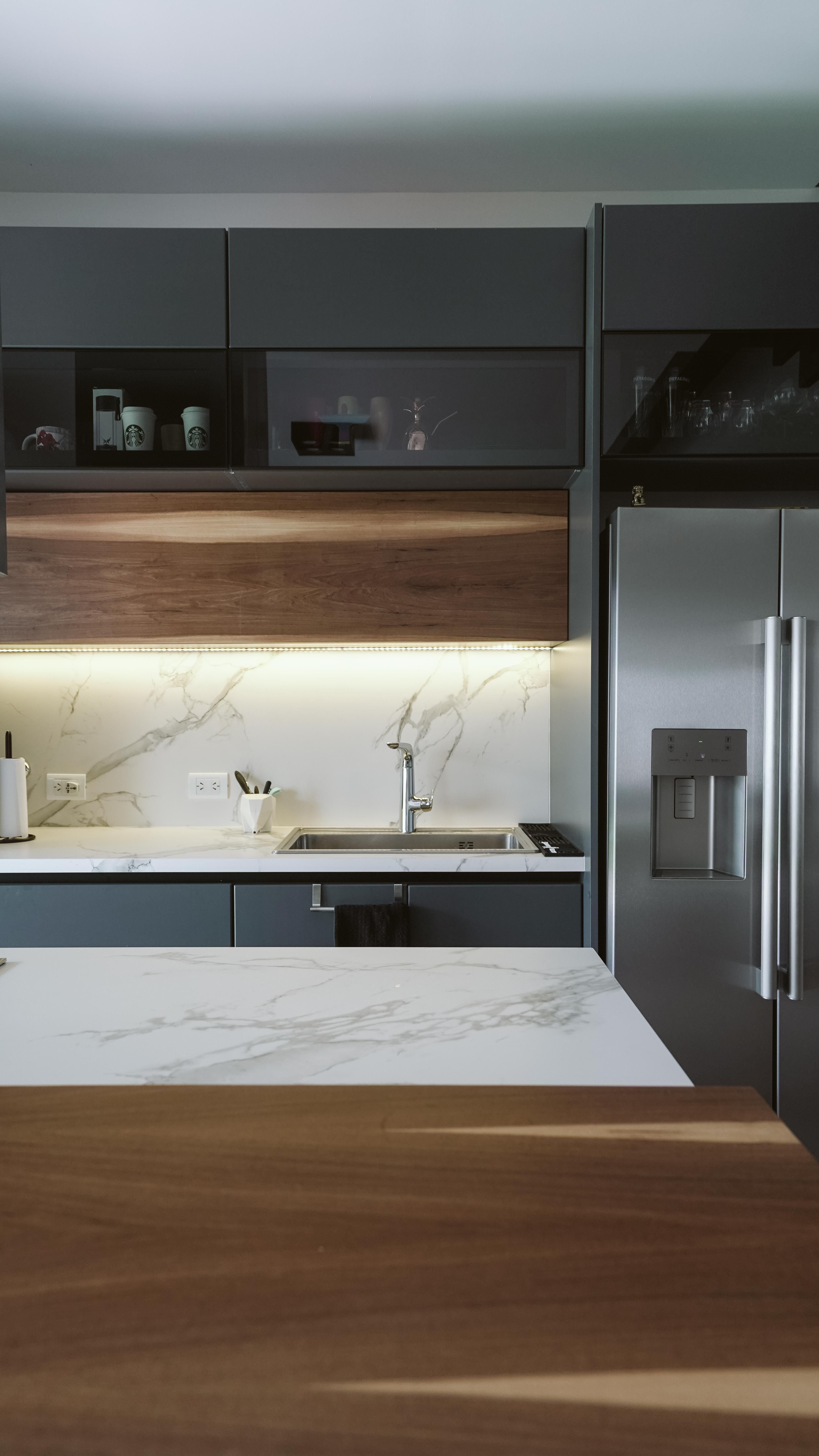 White marble-look countertop and backsplash with an undermount sink between dark gray kitchen cabinets