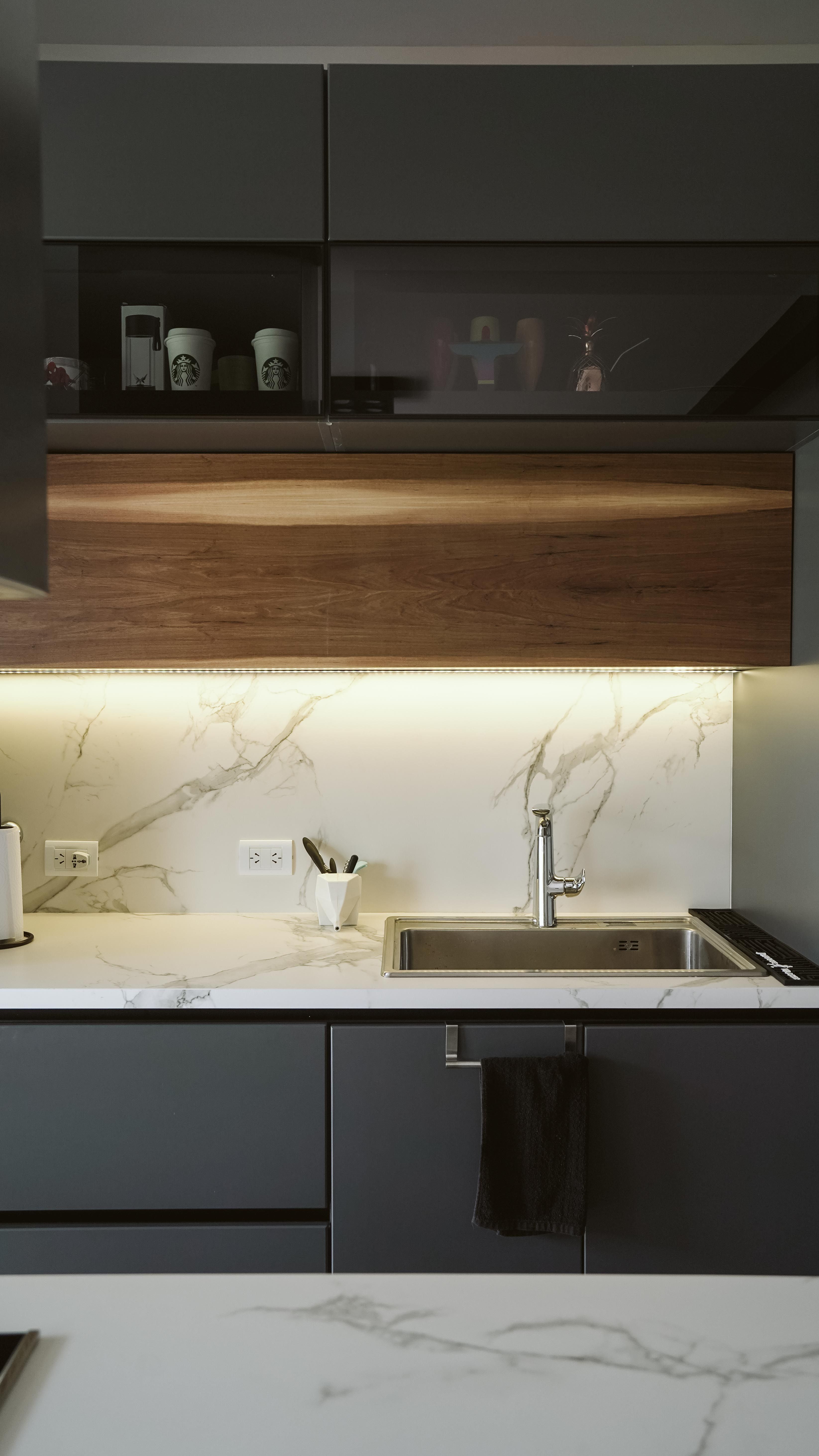 Dark gray kitchen with a white marble-look island countertop and a walnut accent panel