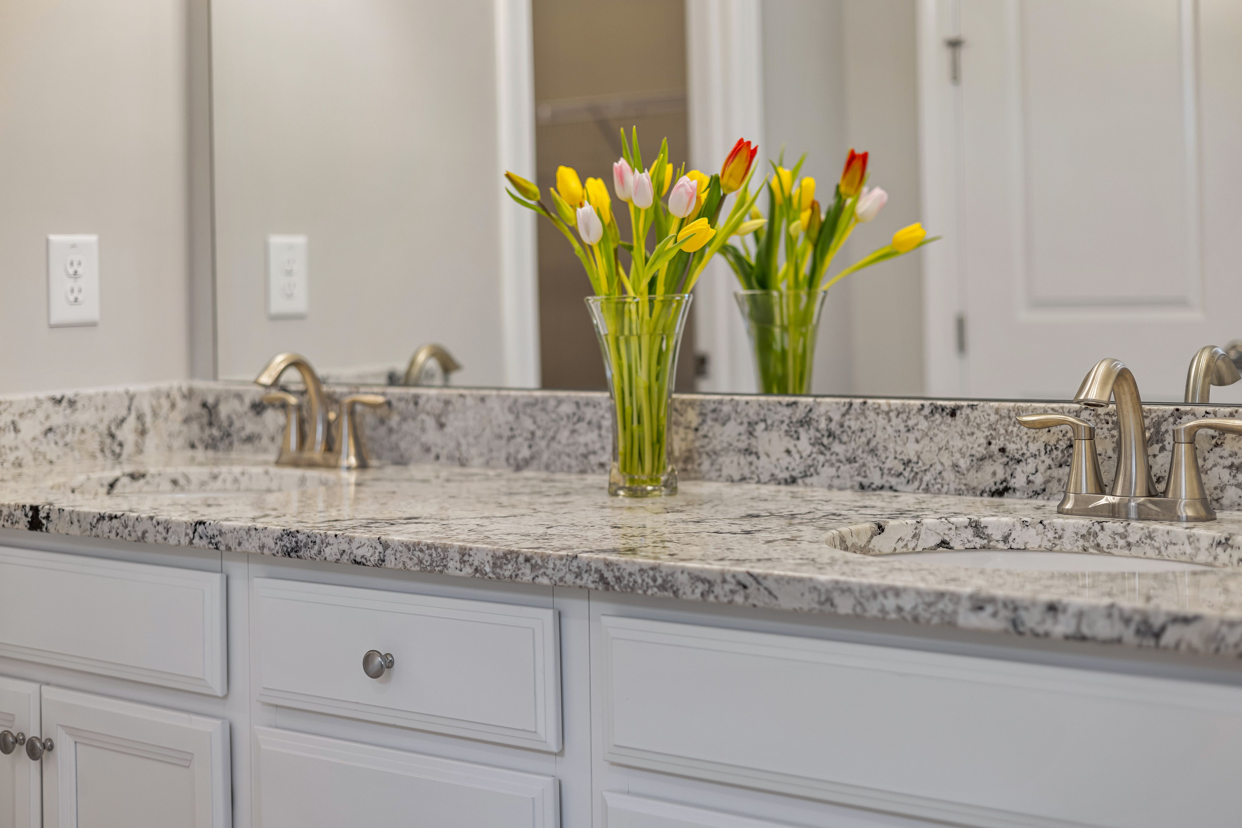 White vanity countertop on dark wood shaker cabinets with two faucets