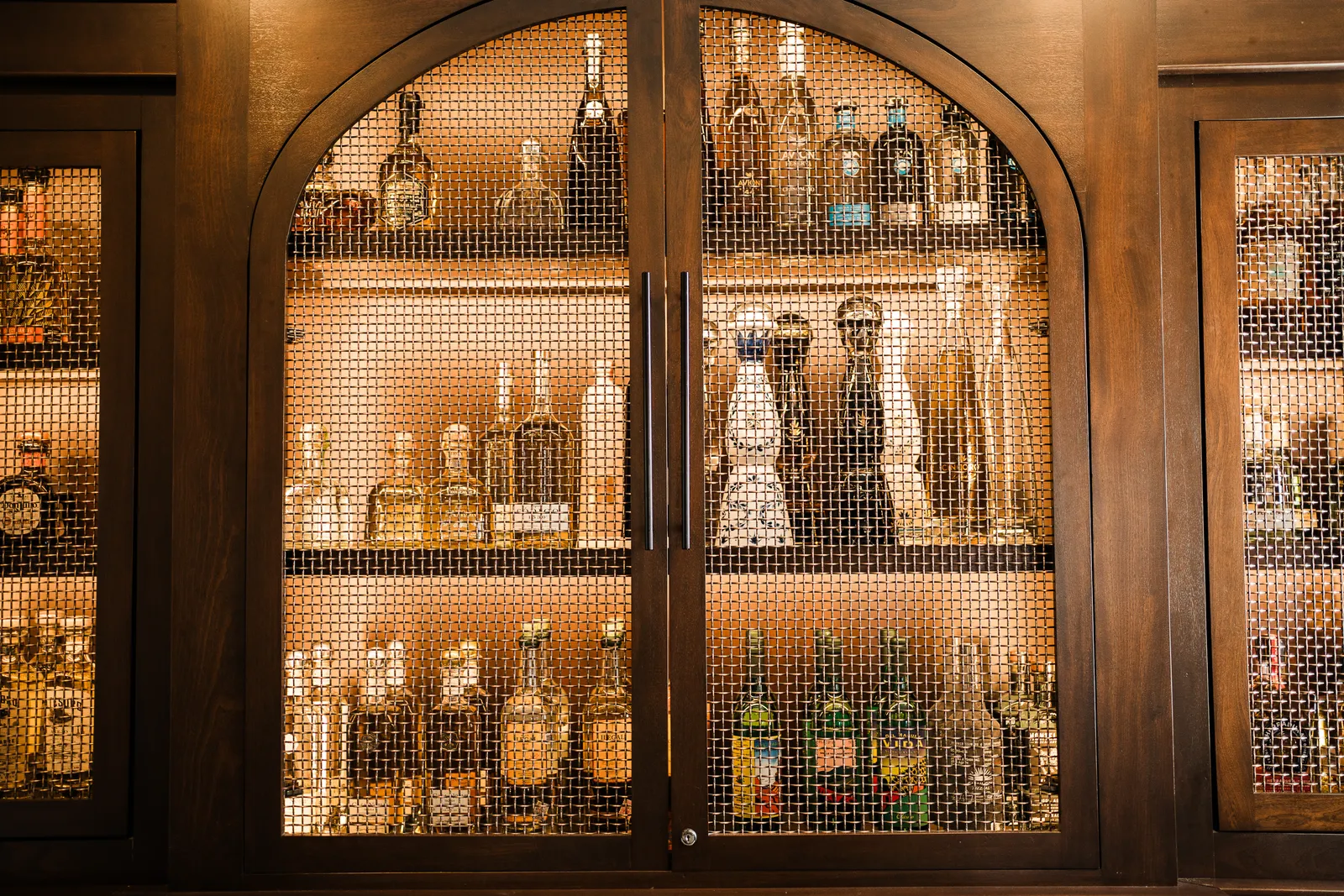 Kitchen Cabinets 18 Wood bar cabinet with arched glass doors and lit shelves of bottles