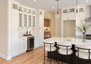 Built-in bar wall with tall glass-front white cabinets, a wine cooler and island seating