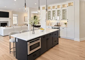 White kitchen with an espresso island and glass-front cabinets, open to the living room